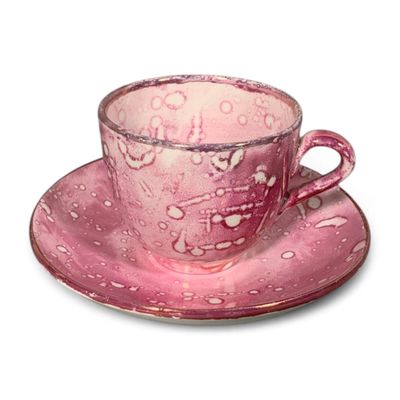 une tasse rose et sa soucoupe posées sur une soucoupe