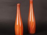 une paire de vases en verre orange sur fond noir