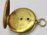 an antique gold pocket watch on a white surface with a chain