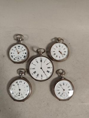 four silver pocket watches sitting on top of a table next to each other
