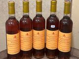 six bottles of wine are lined up on a wooden table