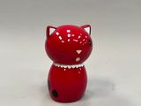 une figurine de chat rouge posée sur une surface blanche
