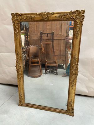 gold framed mirror with a chair and a chair in front of it