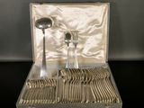 des couverts dans un coffret en argent, posés sur une table avec un fond noir