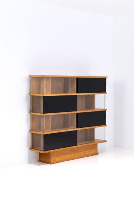 une photo d'une étagère en bois avec des tablettes noires dans une pièce blanche