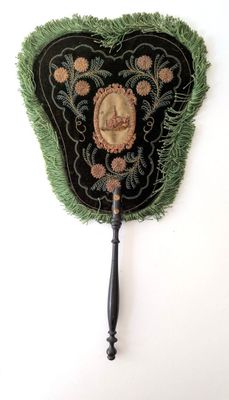 un éventail noir et vert sur lequel est représentée une femme