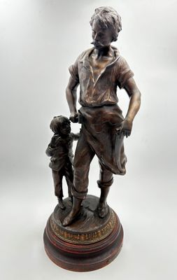 une statue antique en bronze représentant un homme tenant la main d'un enfant