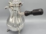an antique silver coffee pot with a wooden handle on a grey background