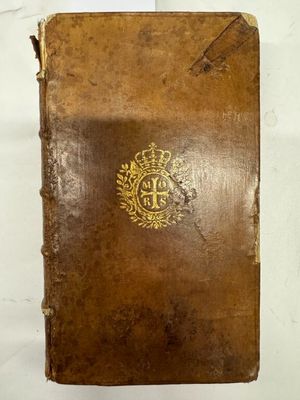 un vieux livre brun portant un emblème doré