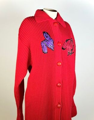 un pull rouge orné de papillons violets et bleus