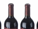 six bottles of wine are lined up in a row on a white surface