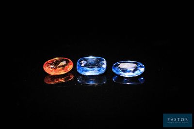 trois pierres précieuses de couleurs différentes posées sur une surface noire