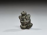 une petite figurine en bronze représentant un singe perché sur un rocher
