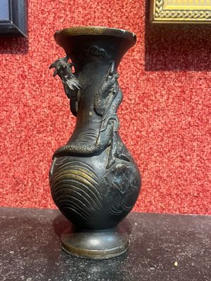 un vase noir orné d'un dragon, posé sur une table