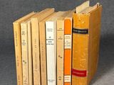 several books are stacked on top of each other on a gray surface