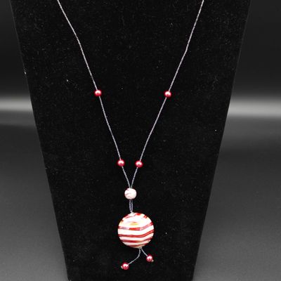 un collier orné d'une perle rayée rouge et blanche sur un mannequin noir
