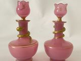 une paire de vases en verre rose avec des touches dorées sur fond blanc