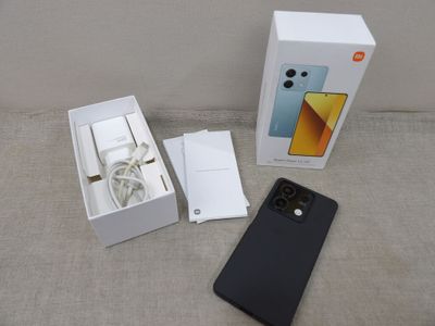 une image représentant une boîte contenant un téléphone et un chargeur branché dessus