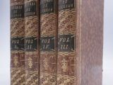 trois vieux livres posés l'un sur l'autre sur une surface blanche