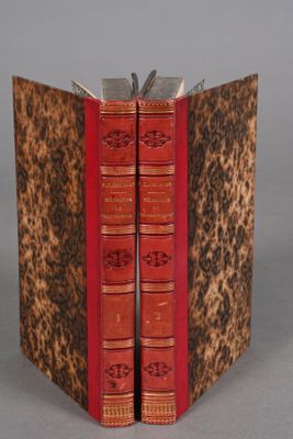 two red books sitting on top of each other on top of a table