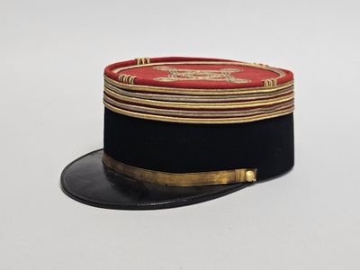 un chapeau noir orné de galons dorés et un haut-de-forme rouge