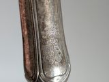 close up of the handle of a silver plated spoon on a gray background