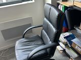 a black office chair sitting in front of a book shelf