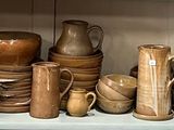 une étagère sur laquelle sont disposées de nombreuses pièces de poterie de styles variés
