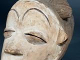 a close up of a wooden mask on a table