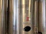 Plusieurs cuves en acier inoxydable sont alignées à l'intérieur d'un bâtiment