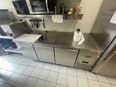 un plan de travail en acier inoxydable dans une cuisine, surmonté d'un micro-ondes