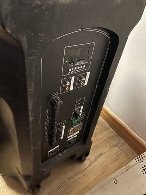 une enceinte noire posée sur une table en bois