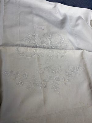 two sheets of white linen with embroidered flowers on them