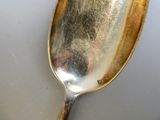 une cuillère en argent avec un manche sur une surface blanche