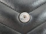 the back of a black purse with a metal button on it
