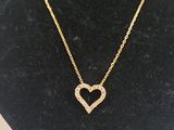 a gold heart necklace on a mannequin display