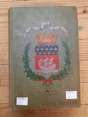 un gros plan sur un livre posé sur une table en bois, avec un blason