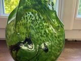 un vase vert posé sur une table en bois près d'une fenêtre