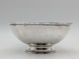a silver bowl on a stand on a white surface