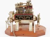 une petite maquette de machine à vapeur posée sur un socle en bois