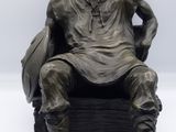 une statue en bronze représentant un homme assis sur une chaise