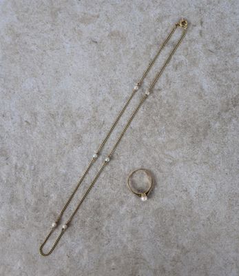 un gros plan d'un collier et d'une paire de boucles d'oreilles posés sur une surface en béton