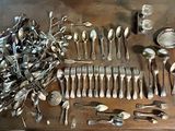 de nombreuses cuillères en argent et de nombreuses cuillères ordinaires sur une table