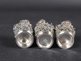 three silver vases sitting next to each other on a black surface