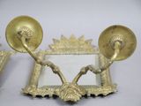 a gold colored mirror with two candles on it
