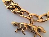 a close up of a gold chain bracelet with a dog charm