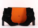 a pair of black sued ankle boots with buckles and a box
