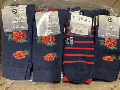 three pairs of socks with roses on them are in a box