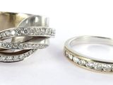 two wedding rings with diamonds on them on a white surface