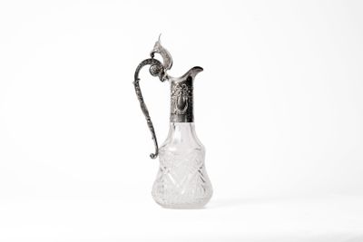 a glass pitcher with a metal handle on a white surface